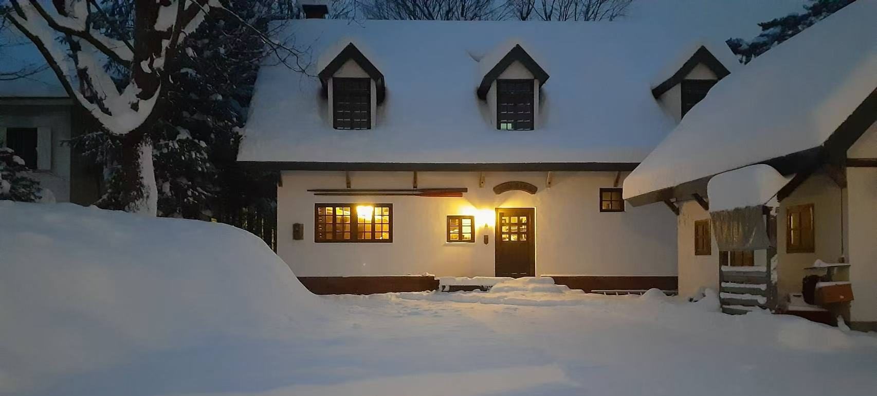 雪に覆われた白馬村の宿泊施設Maykissの夕暮れの外観